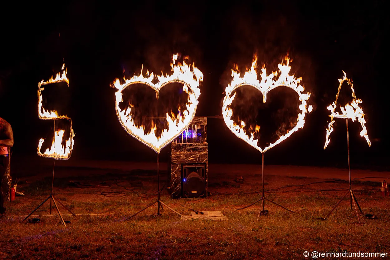Brennende Initialen und zwei Flammenherzen bei Nacht