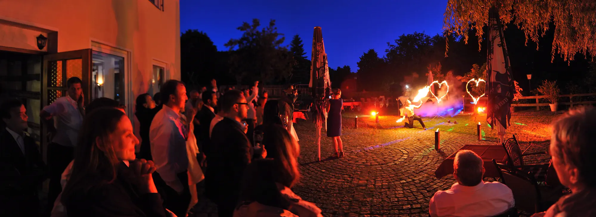 Hochzeitsgäste erleben eine Feuershow mit Flammenherzen am Abend